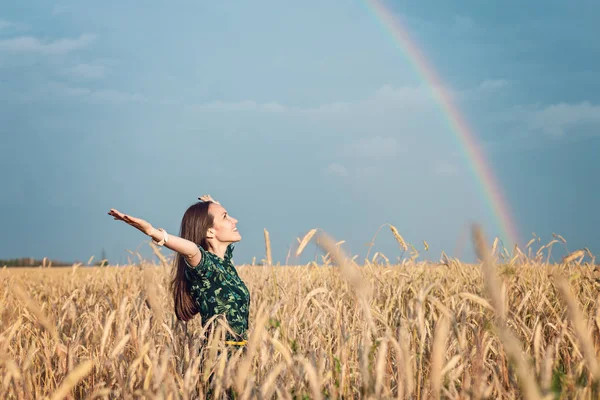 Freedom. Woman with open hands smiling looking at the sky against the rainbow.