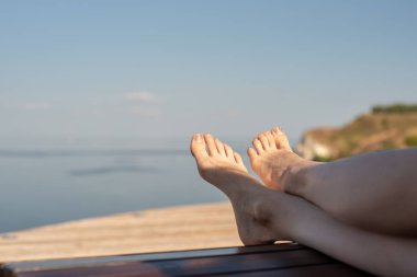 Güzel tabaklanmış kadın ayak deniz bulanık bir arka plan üzerinde şezlong üzerinde