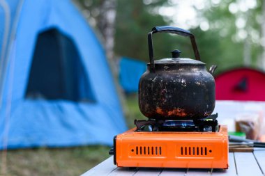 Gaz yakıcı bir çadır doğada arka plan üzerinde üzerinde yanmış çaydanlık demir, kamp Odaya Servis Kahvaltı