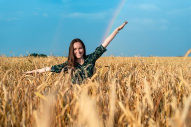 Frontal çavdar spikelets bir gökkuşağı arka plan üzerinde bir alana bir kadın portresi.