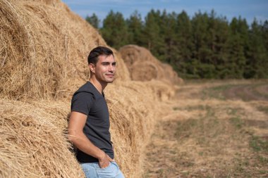Gri t-shirt adam çiftçi gülümseyen varoluş portresi saman görünüyor alan, haymaking, hasat, endüstri kavramı sırtı ile standları