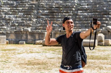 Genç adam gülümseyerek, kamera, barış, sosyal ağlar, Gezgin bir sembolü olarak bir selfie alarak bir kap içinde