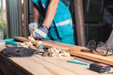 Carpenter'ın home atölye, ağaç işleme masada, dostum eldiven ve tulum ile görüntü'nün, bir planer seçici odak araçları.