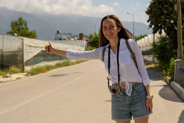 woman on the side of the road catches a passing car, hitchhiking