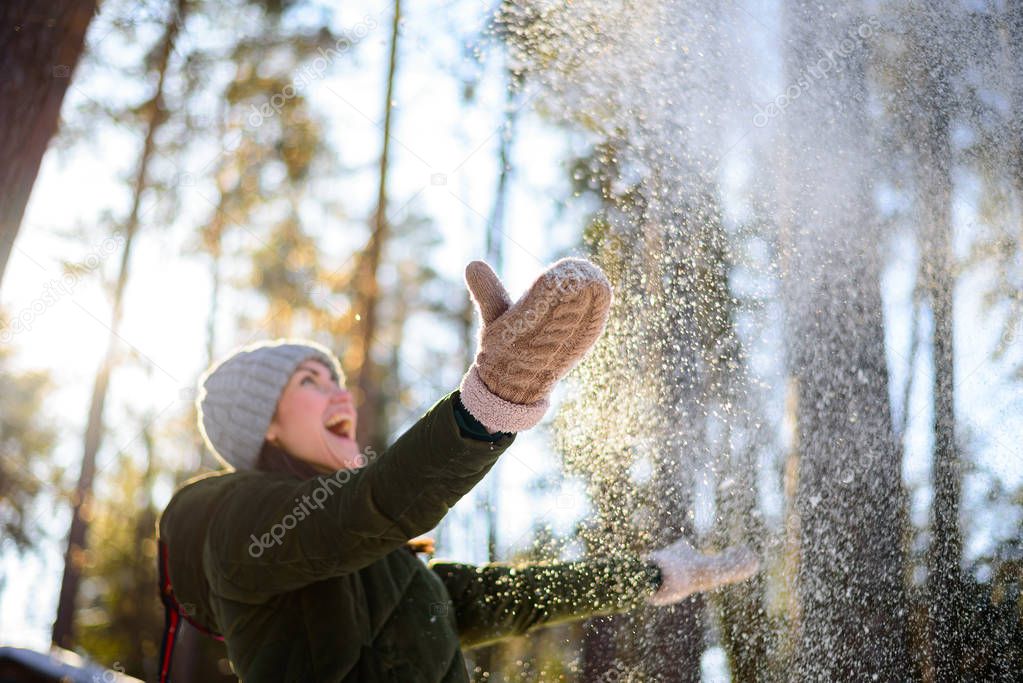 Girl enjoys winter, frosty day, snow. playing with snow, a woman throws white, loose snow into the air. Walk with winter forest.