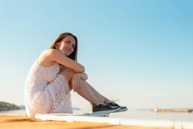 Genç esmer dizlerinin ufuk, seyir sarılma iskelede oturup gün batımı gün gülümseyerek