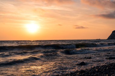 Su fırtına rüzgar dalgaları ile üzerinde parlak pembe-turuncu şafak.