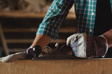 Erkekler Close-up odun kesmek el uçak ile çalışma eldiven eller. ağaç işleri, çatı kaplama, inşaat, endüstriyel arka plan