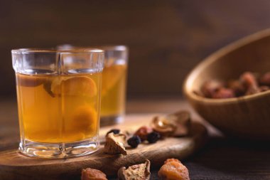 Cam bardak ve karışık Kuruyemiş ahşap arka plan üzerinde ahşap bir kase meyve kompostosu. Seçici odak. Sağlıklı içecek