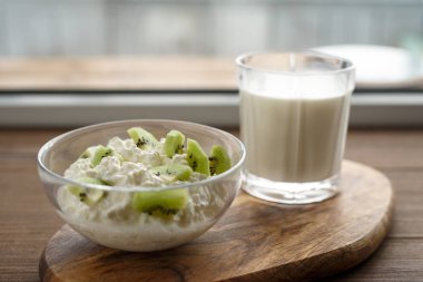 Yakın - up kivi süzme peynir ve süt pencere, kavram sağlıklı gıda tarafından ahşap tahta üzerinde