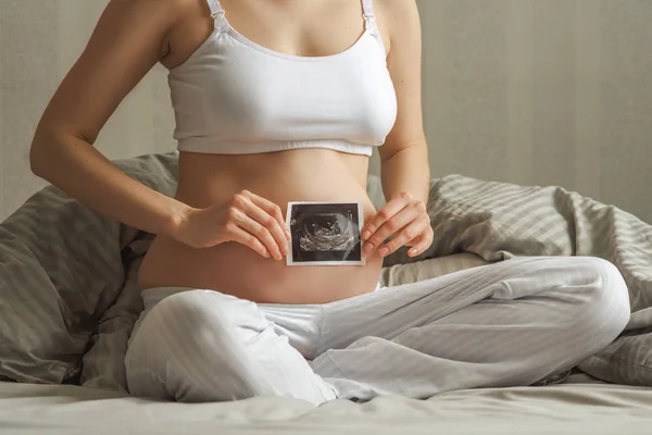 妊婦の超音波写真が付いているベッドの上に座ってのクローズ アップ 母性の概念 — ストック写真