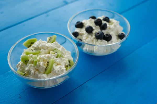 牛奶产品 奶酪与浆果和水果在碗在蓝色背景 健康饮食早餐 — 图库照片