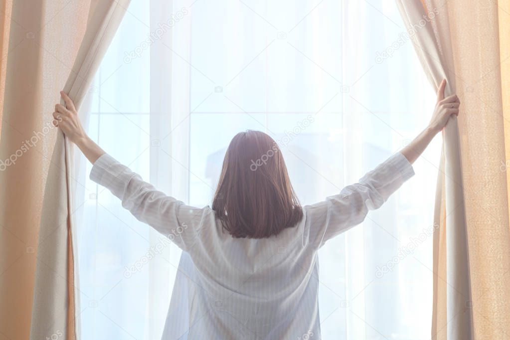 close-up of a girl with dark hair opening the curtains