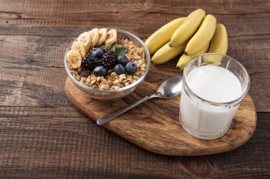 ahşap arka planda muz, çilek ve bardak süt ile granola