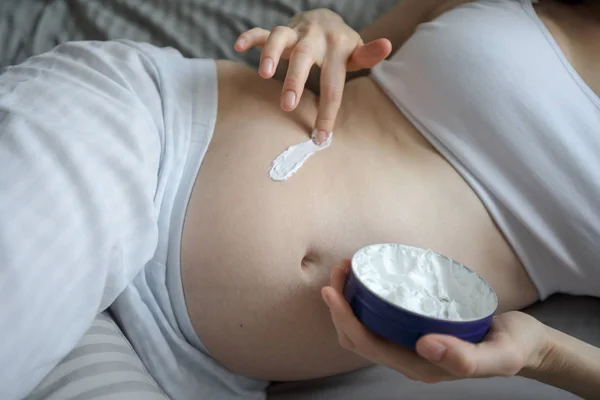 Donna incinta utilizza la crema per le smagliature sulla pancia — Foto Stock