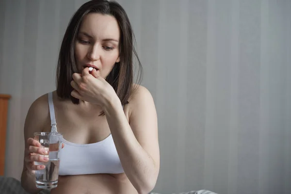 Schwangere nimmt Tablette mit Glas Wasser auf den Händen — Stockfoto