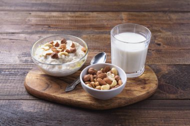 ahşap arka planda kahvaltı için fındık ve bardak süt ile yulaf ezmesi