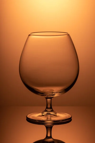 オレンジ色の背景に垂直画像の空のワイングラス — ストック写真