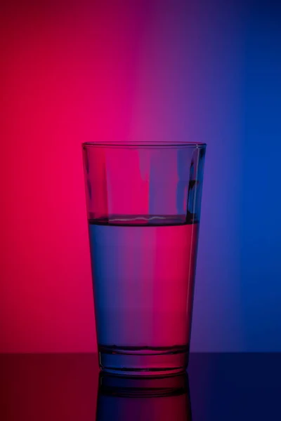 Imagen vertical vaso de agua sobre fondo rosa azul — Foto de Stock