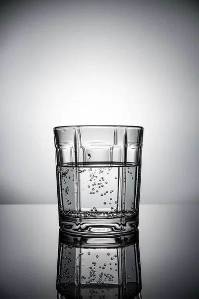 Vaso de agua con burbujas sobre fondo gris — Foto de Stock