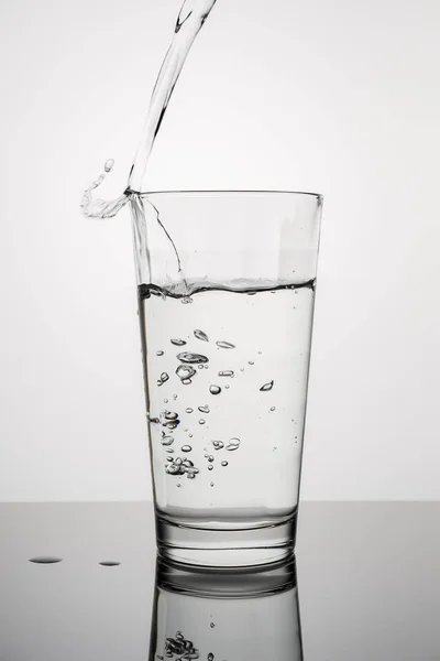 Vertikální obraz sklenice vody na šedém pozadí — Stock fotografie