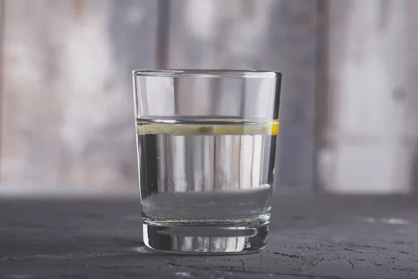 Cerrar vaso de agua con limón sobre fondo gris — Foto de Stock