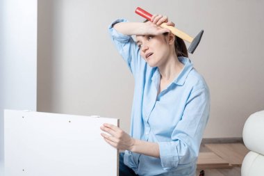 Elinde bir çekiç ile yorgun bir esmer kadının portresi, ter ile alnını silecek, mobilya montaj