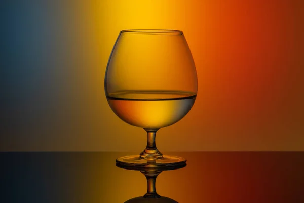 Um copo de vidro de água em um fundo multicolorido — Fotografia de Stock