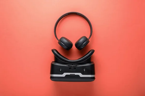 Minimalistiska design prylar på röd bakgrund, trådlösa hörlurar och VR-glasögon — Stockfoto