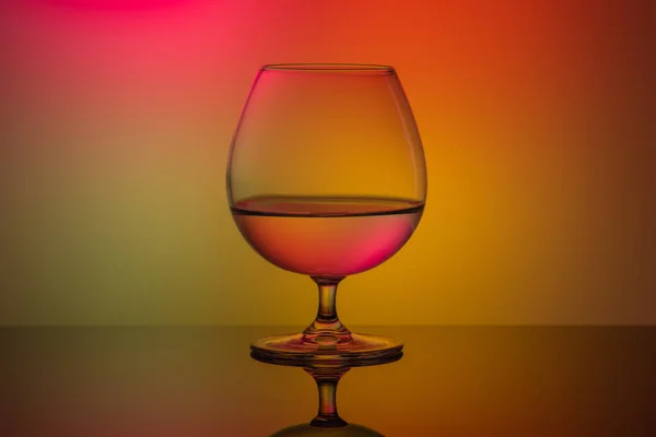 Een glas op de tafel op een multi-gekleurde achtergrond — Stockfoto