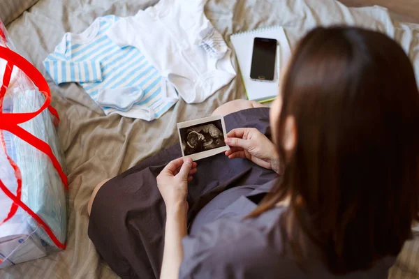 Vista superior de una mujer embarazada recoge cosas en el hospital, viendo una imagen de ultrasonido — Foto de Stock