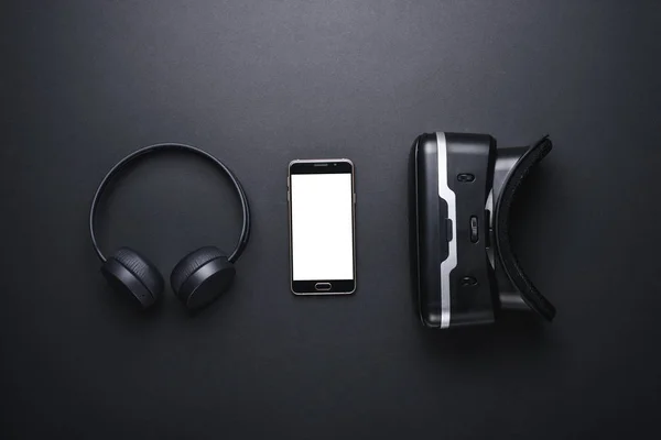 En uppsättning enheter för moderna spelare. trådlösa hörlurar, smartphone, VR-glasögon på svart bakgrund med app layout — Stockfoto