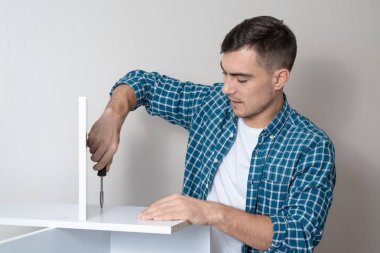 Bir tornavida ile bir kafes bir gömlek içinde genç bir adam uzay bir kopyası ile bir masaüstü toplar