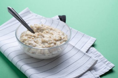 Gıda minimalizm. Kopya alanı ile yeşil arka plan üzerinde kaşık ile pembe plaka yulaf yulaf ezmesi