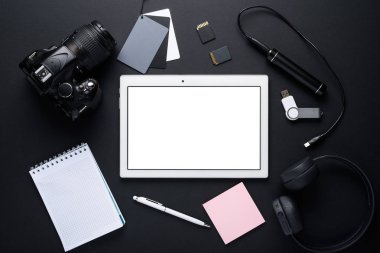 Fotoğrafçı Gadget 'ları. Düzen altında tabletin üst görünümü, kamera DSLR, kablosuz kulaklıklar, güç Bankası, Notebook ve gri kart