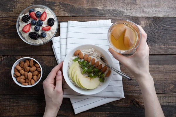 早餐时女性手的顶视图,杏仁和苹果燕麦片,坚果,浆果,复合 — 图库照片