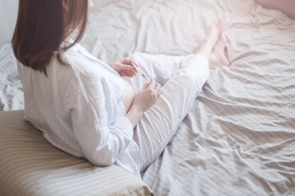 Молодая беременная женщина в постели с термометром, место для смс — стоковое фото