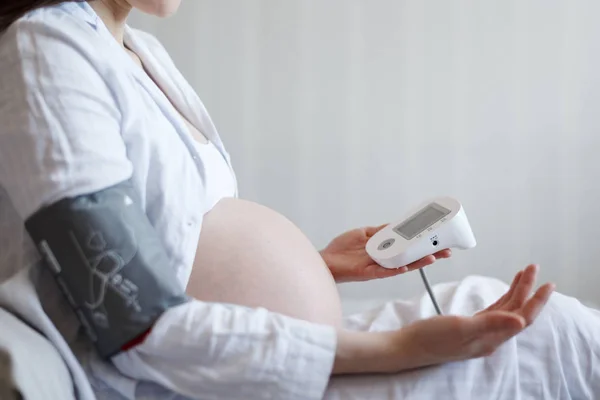 Vista laterale primo piano dell'addome della donna incinta, misura la pressione sanguigna con sfigmomanometro, senza faccia — Foto Stock