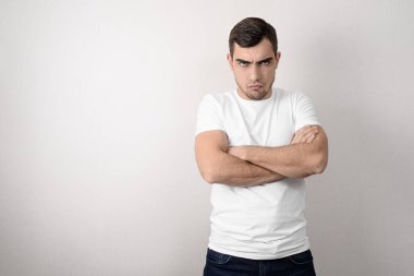 Boşluk bir kopyası ile beyaz bir t-shirt katlanmış kollar ile ciddi, öfkeli genç adamın portresi