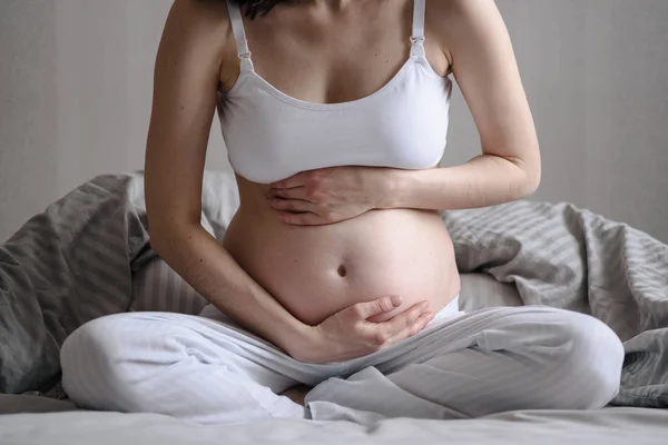 Närbild av gravida kvinnans mage håller händer, böjd över i smärta, första trimestern problem — Stockfoto