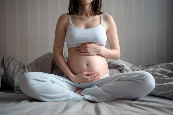 Κοντινό-up της εγκύου γυναίκα κρατώντας την κοιλιά της με τα χέρια της πάνω και κάτω, διαλογισμός — Φωτογραφία Αρχείου