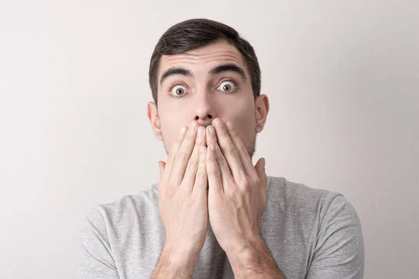 Close up portrait of man with shocked face covers his mouth with his hands — Stock Photo, Image