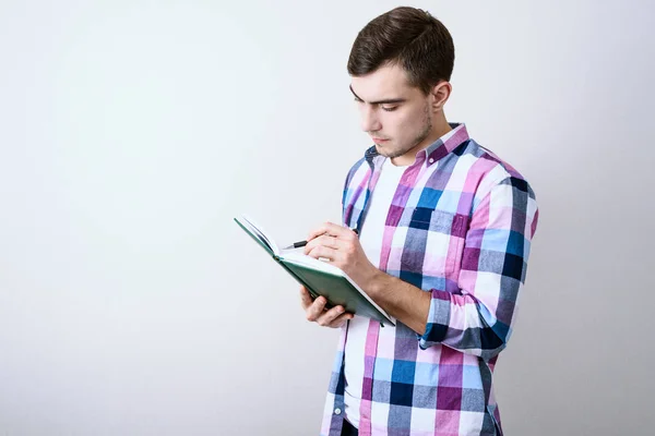 Jonge blanke man student studie lezingen notities over grijze achtergrond met Kopieer ruimte — Stockfoto