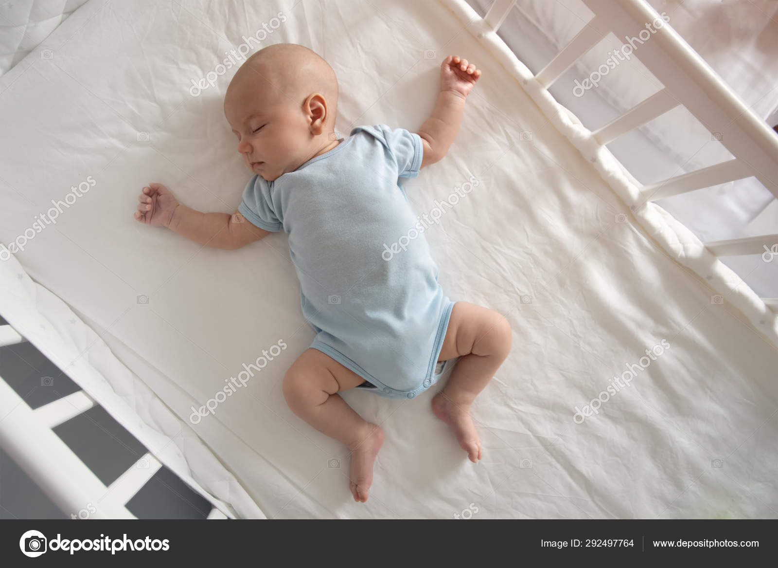 Top view wide angle sleeping newborn baby lies in a crib arms and legs