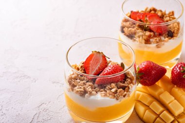 mango smoothie, ricotta peyniri, granola ve çilek güzel dilimlenmiş mango ve pembe arka plan üzerinde kopya alanı meyve tatlı ile iki bardak yakın çekim