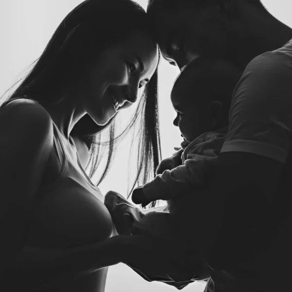 Imagen en blanco y negro de una pareja joven con un bebé recién nacido en sus brazos — Foto de Stock