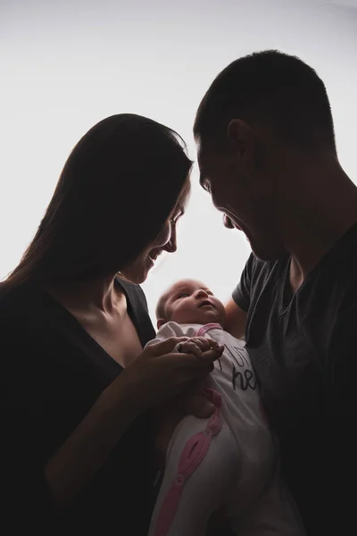 Bir bebek ile sarılan bir çift dikey siluet aile portresi — Stok fotoğraf