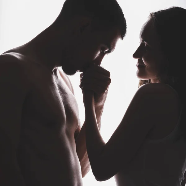 Silhouette portrait of a couple in love, a man holding a woman's hand and kissing — Stock Photo, Image