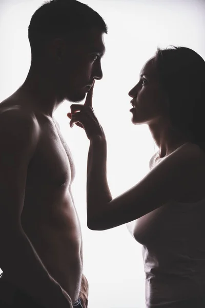Σιλουέτα ενός νεαρού ζευγαριού, η γυναίκα καλύπτει το στόμα της με ένα δάχτυλο άνδρες, δύναμη των γυναικών — Φωτογραφία Αρχείου