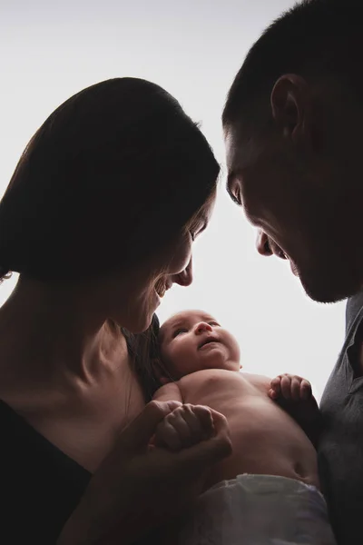 Yeni doğmuş bir bebek ile genç bir çift yakın çekim siluet aile portresi — Stok fotoğraf